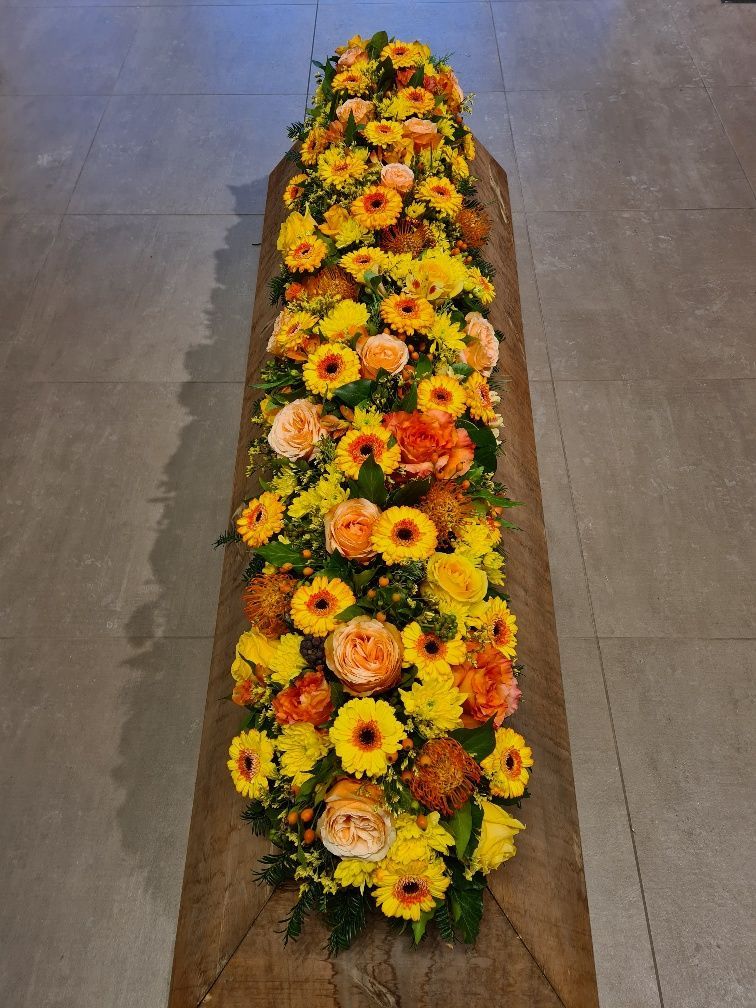 Sargbuketts mit gelben und orangefarbene Blumen