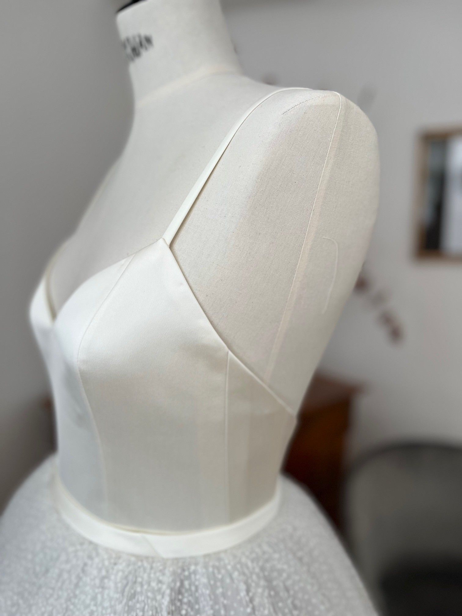 Weißes Brautkleid aus Satin an einer Schaufensterpuppe mit transparenten Netzärmeln und Tüllrock