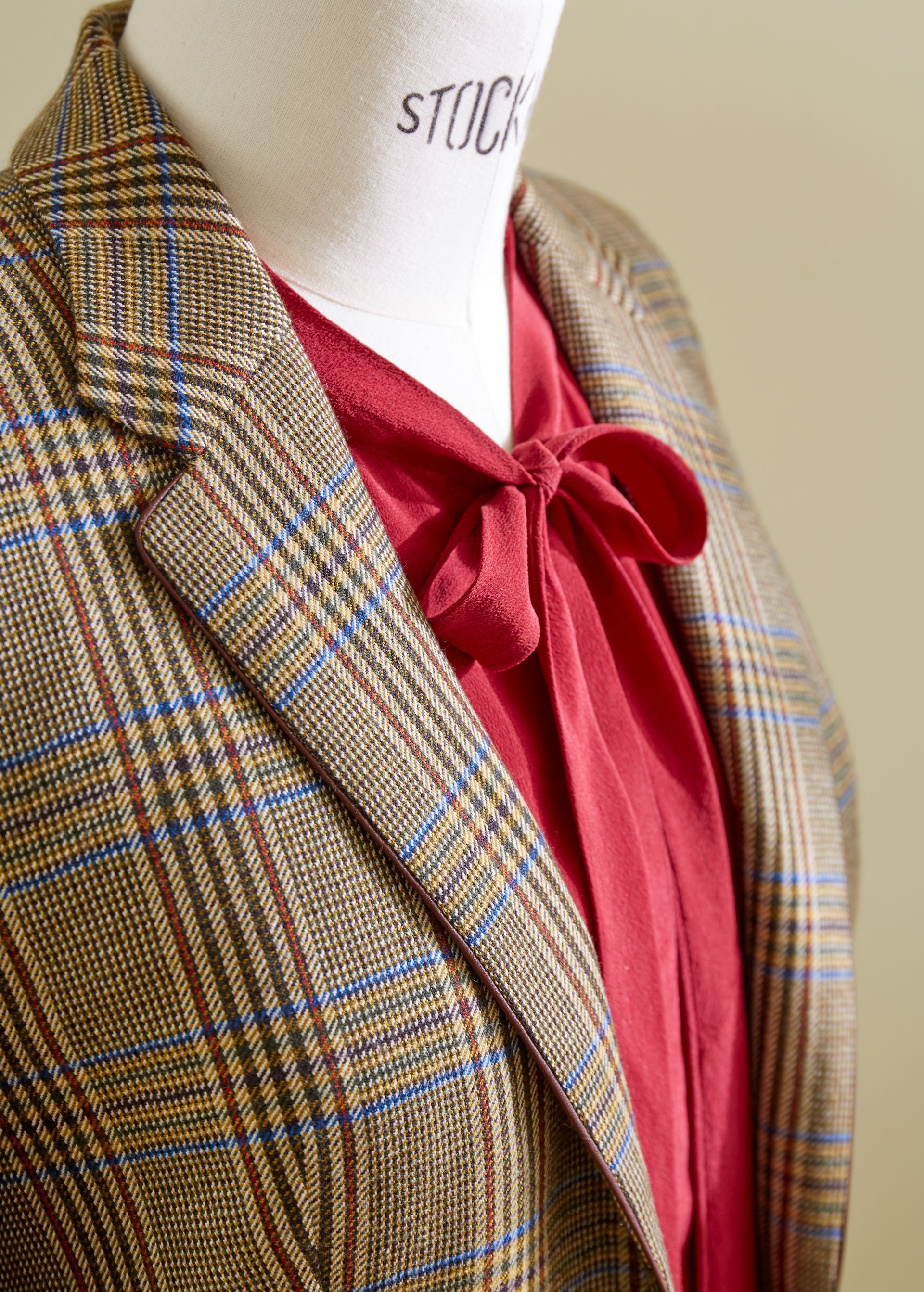 Ein karierter Blazer über einer roten Bluse mit Fliege an einer Schaufensterpuppe