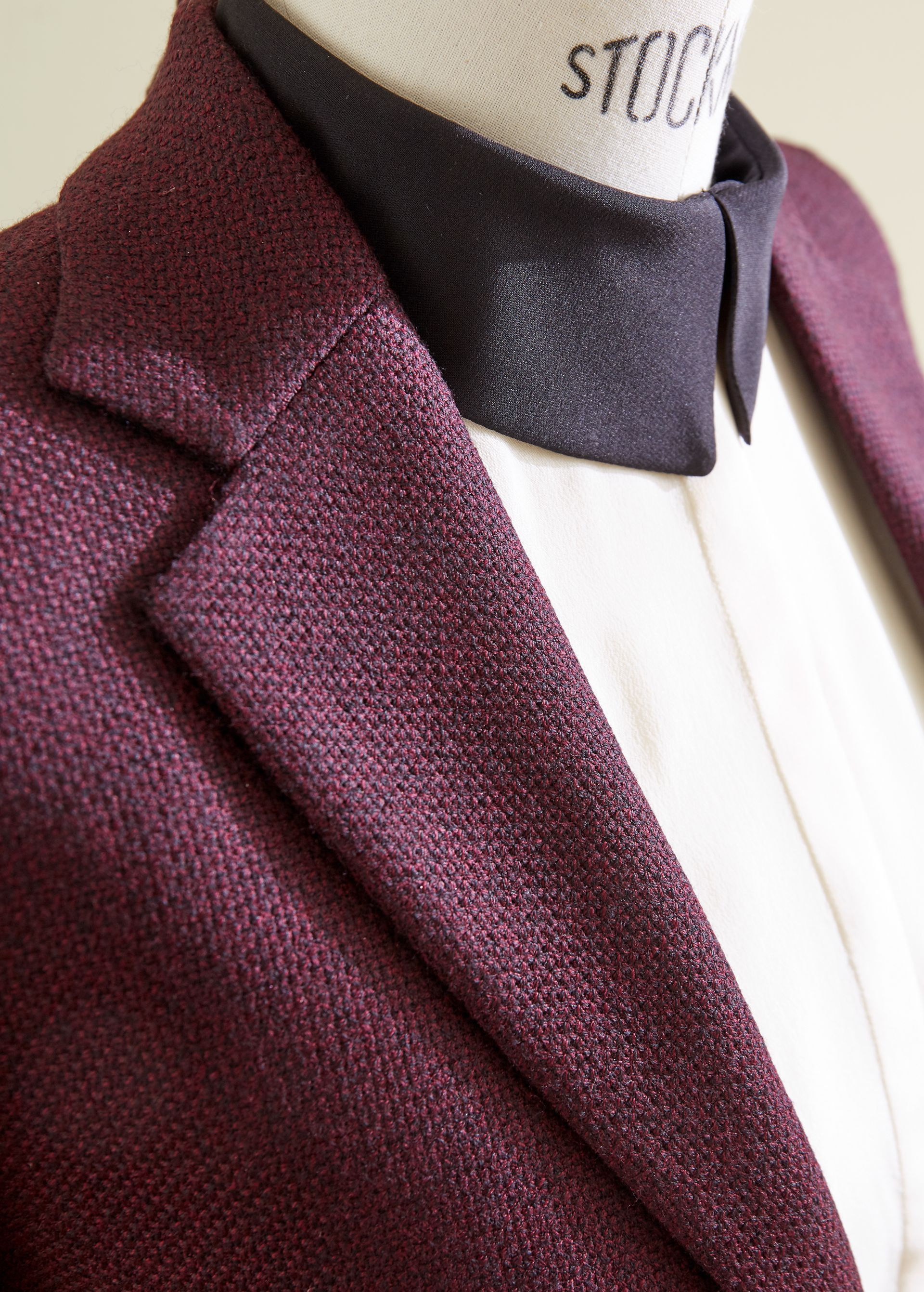 Ein bordeauxroter Blazer mit dunklem Schal an einer Schaufensterpuppe in einer Kleiderauslage