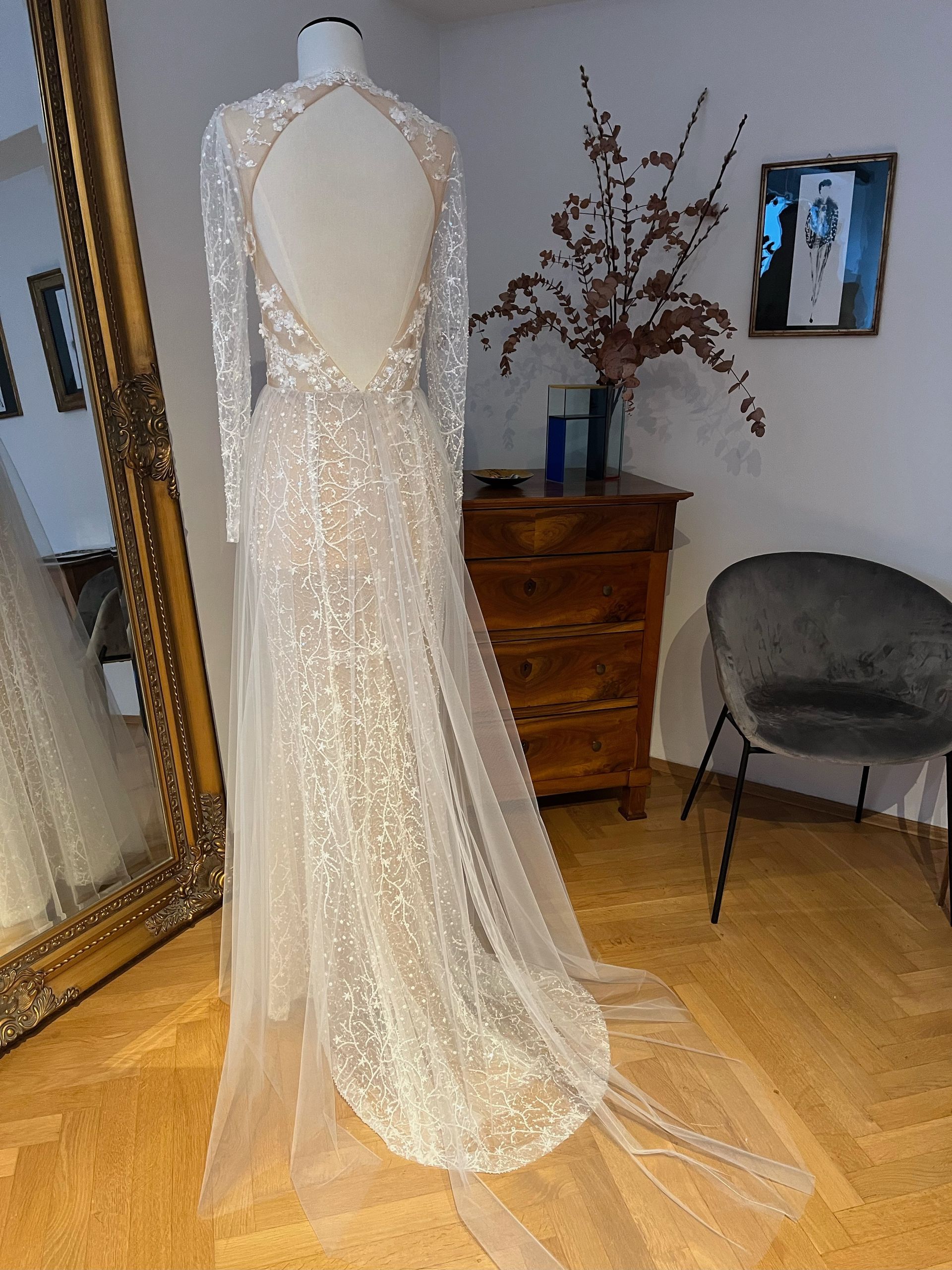 Ein elfenbeinfarbenes, mit Perlen besticktes Brautkleid hängt auf einer Schaufensterpuppe.