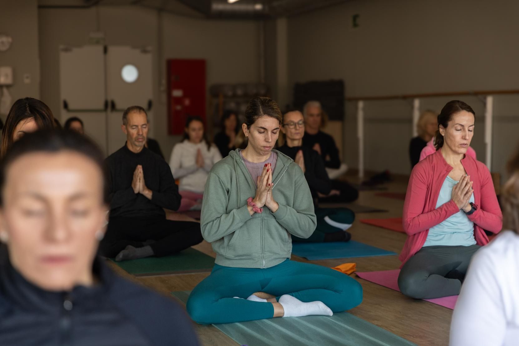 Mujer meditando en un acantilado con vistas al océano al atardecer.