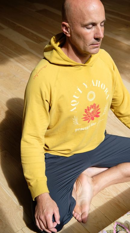 Instructora de yoga sentada en la plataforma, demostrando estiramientos a la clase.