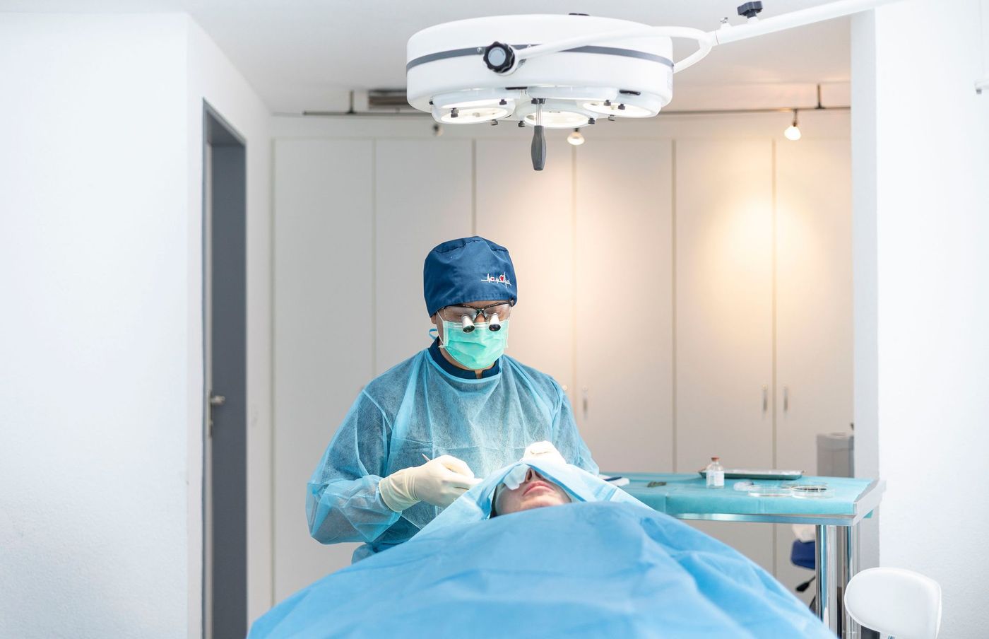 Chirurg in blauer OP-Kleidung operiert in einem hellen Krankenhaus-OP-Saal
