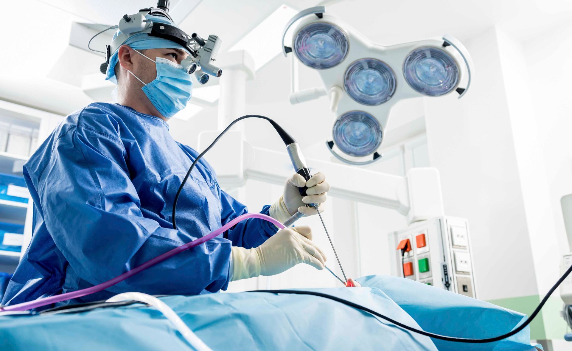 Chirurg benutzt während einer Nasenoperation an einem Patienten unter blauen Abdecktüchern eine Pinzette.