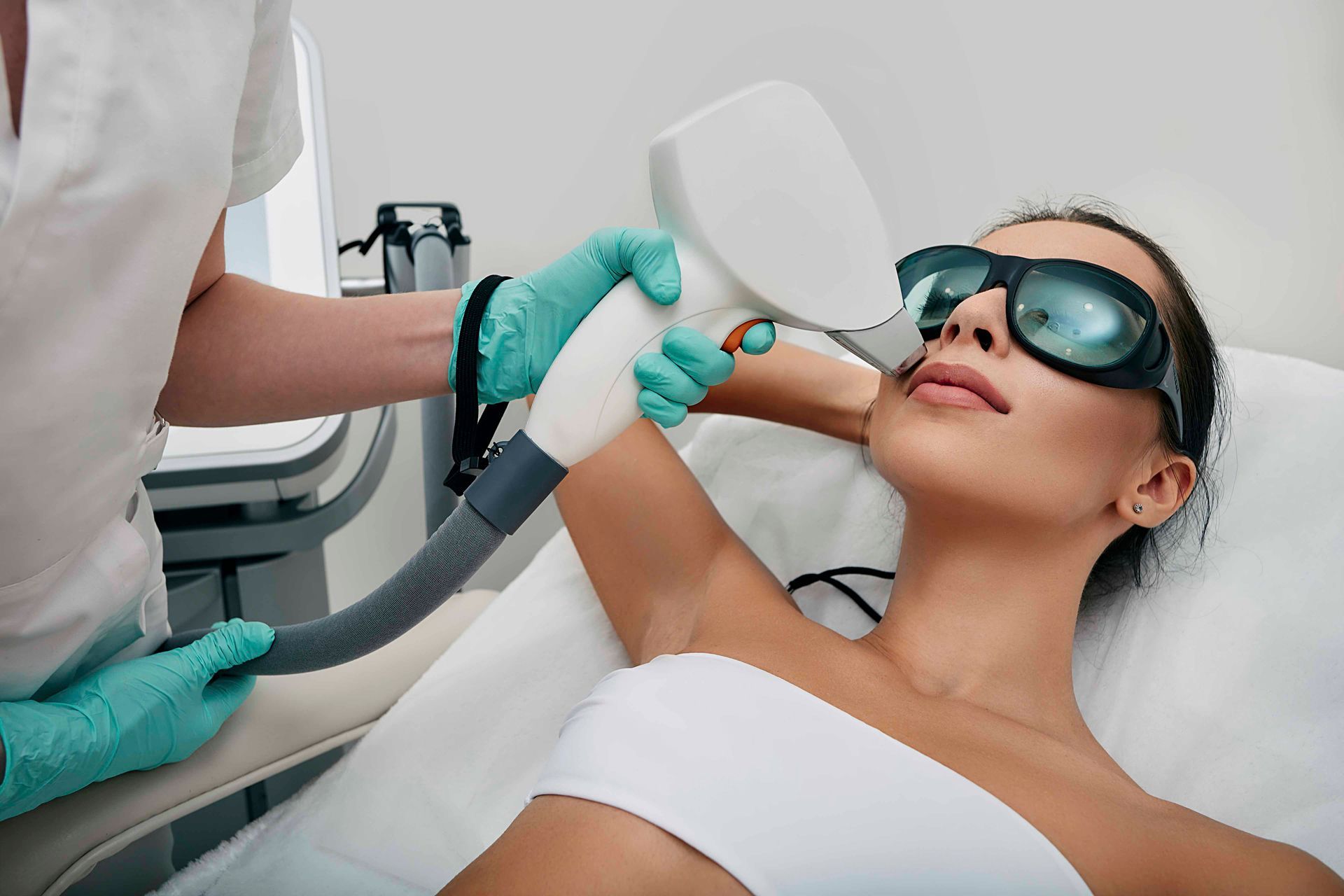 Kosmetische Laserbehandlung an einer Frau mit Schutzbrille in einer Klinik