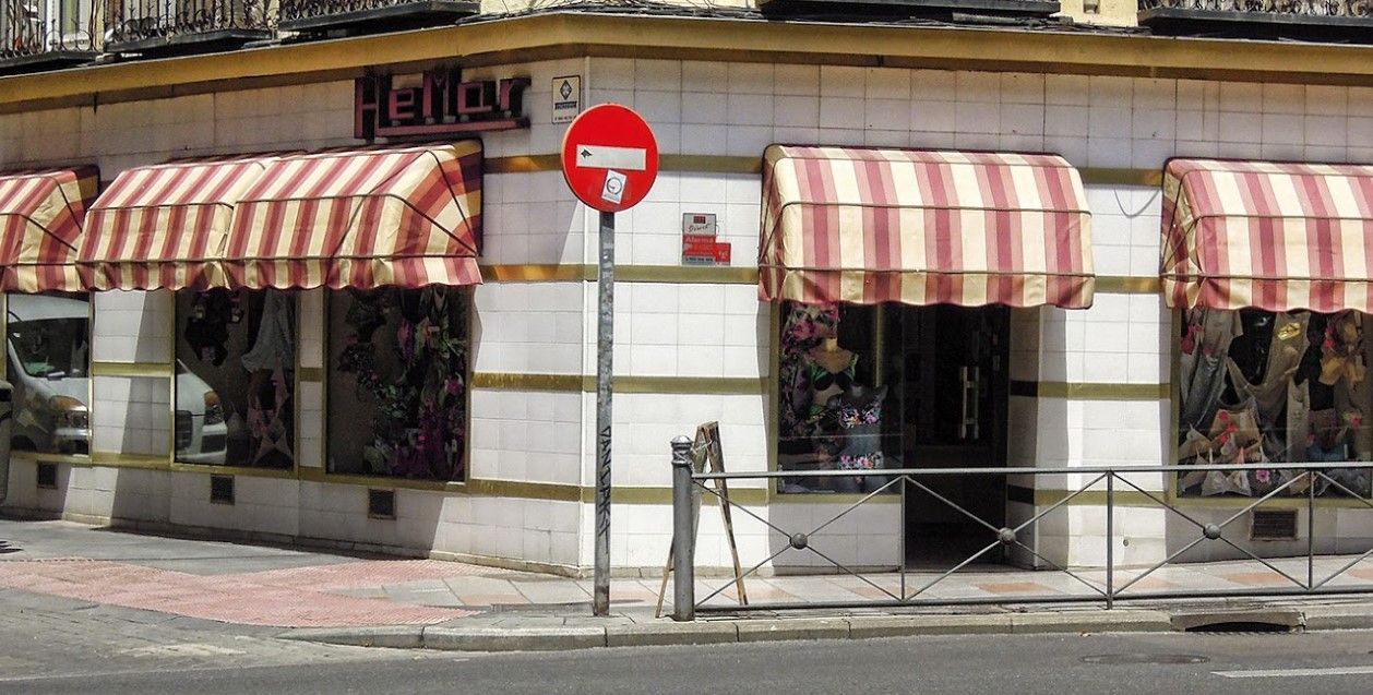 Un escaparate con toldos a rayas y un cartel de no entrar
