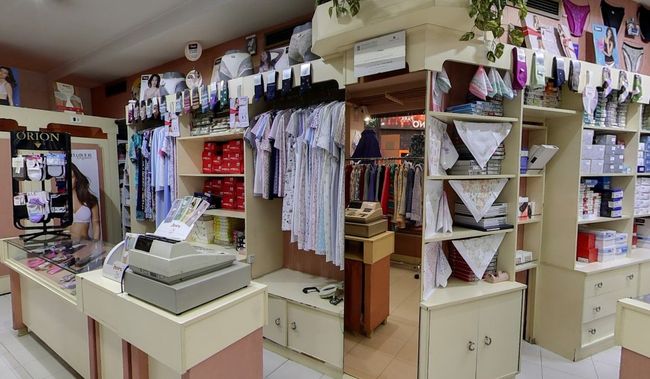 Una tienda llena de mucha ropa y una caja registradora.