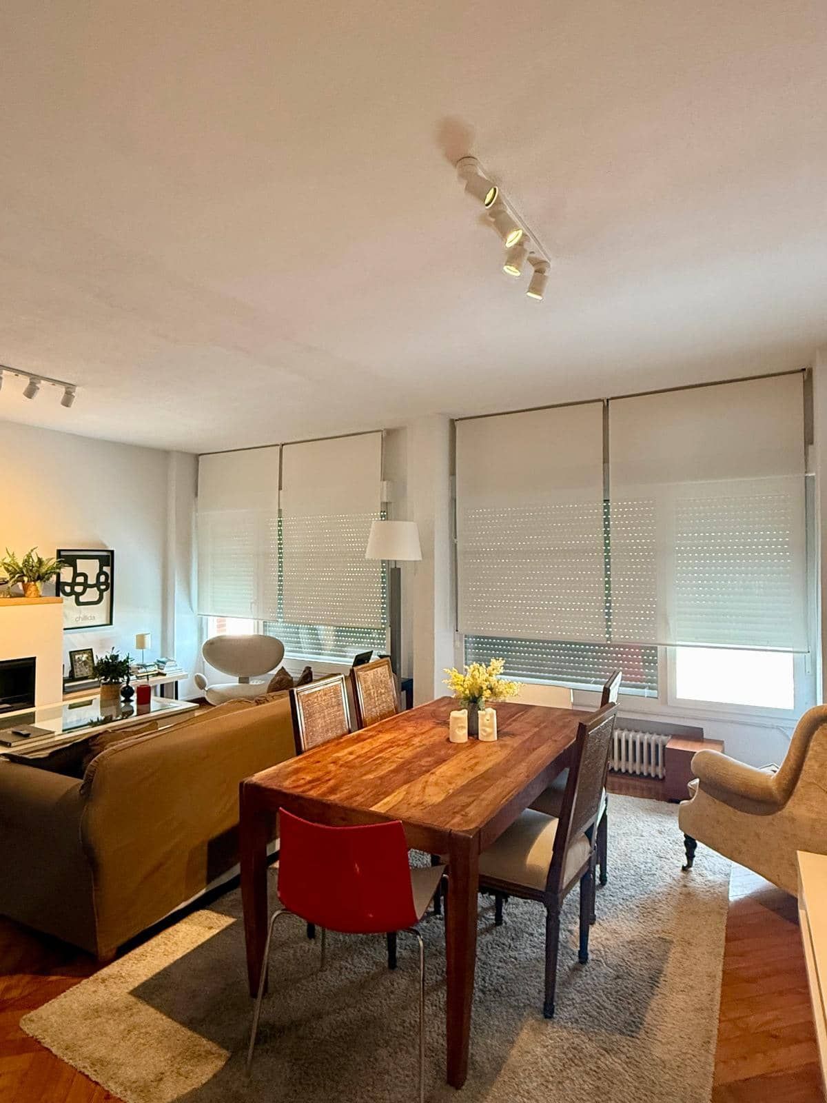 Sala de estar con mesa de comedor, sofá y ventana con persianas.