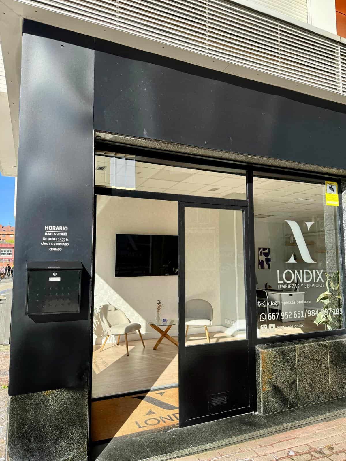 Fachada negra con puerta de cristal y el logo de 