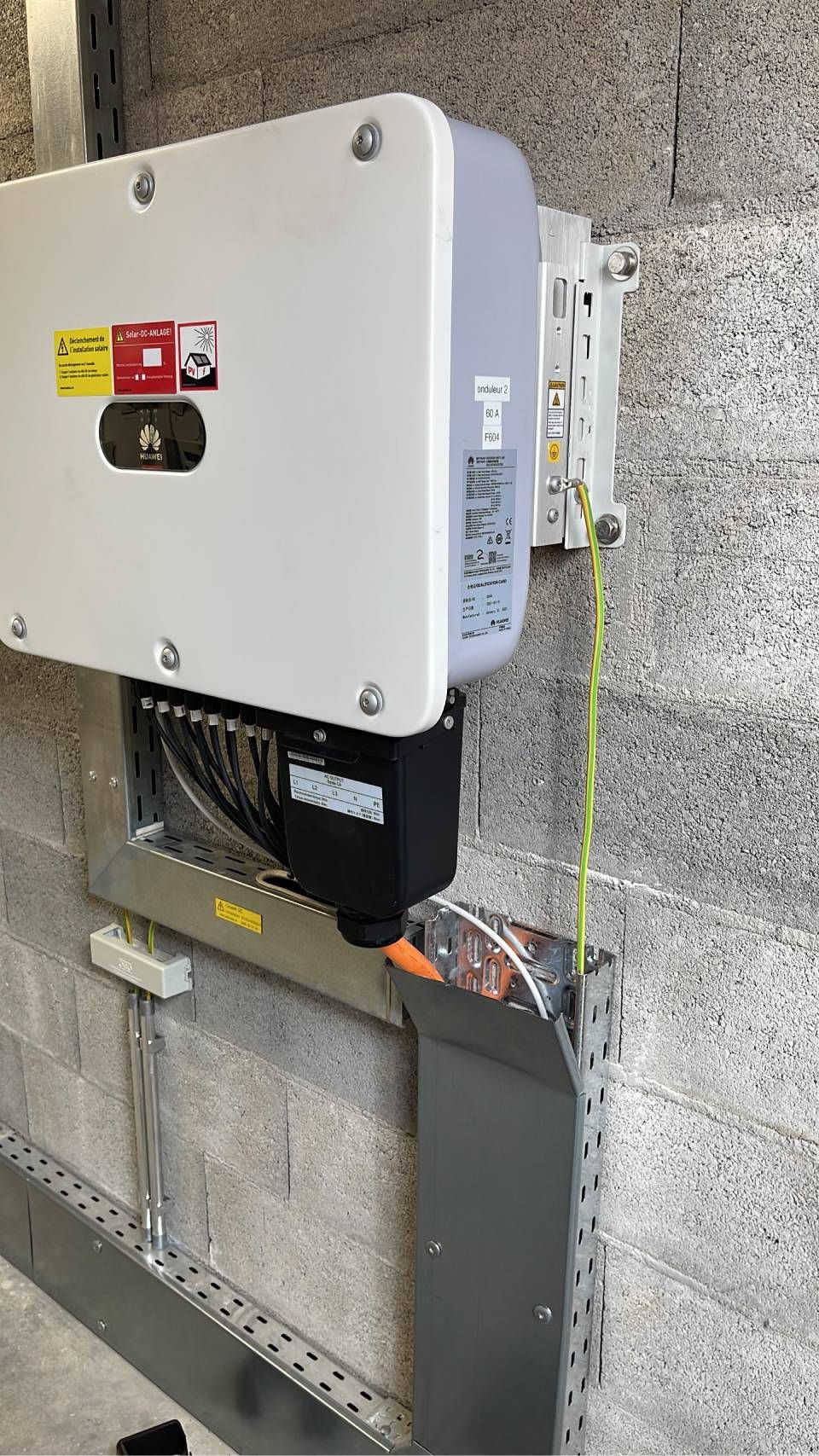 Onduleur de panneau solaire installé sur un mur en béton avec câblage électrique.