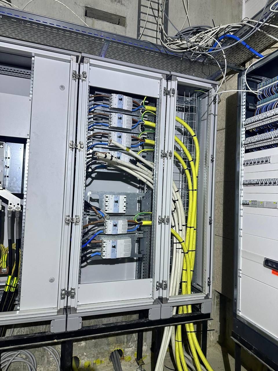 Tableau électrique avec câblage, principalement des câbles blancs et jaunes, dans un environnement industriel.