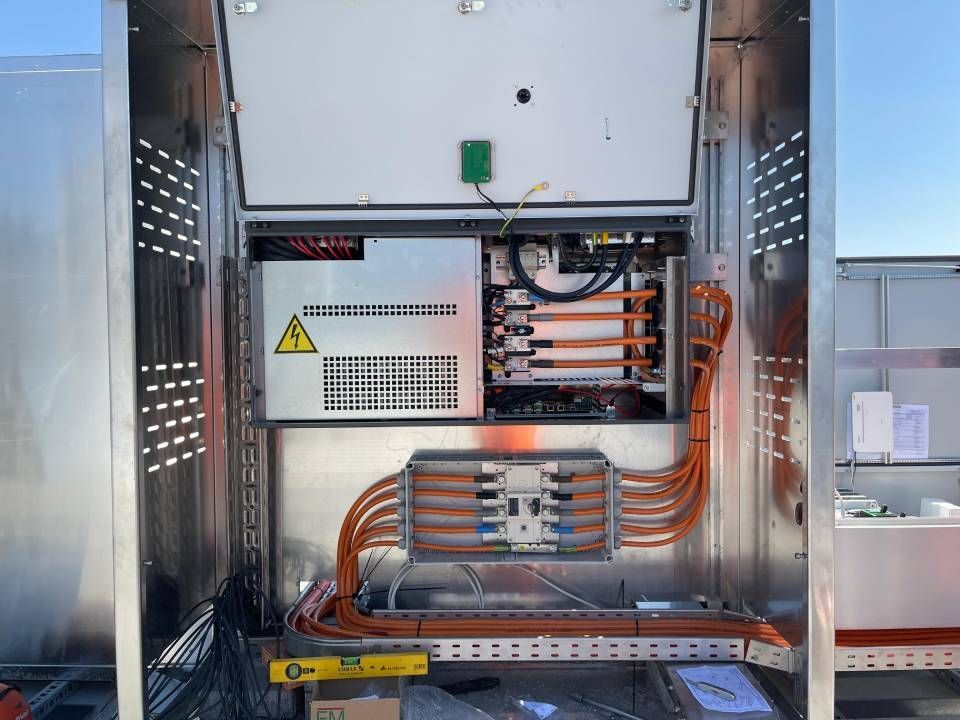 Armoire métallique ouverte contenant des composants électriques et des câbles orange.