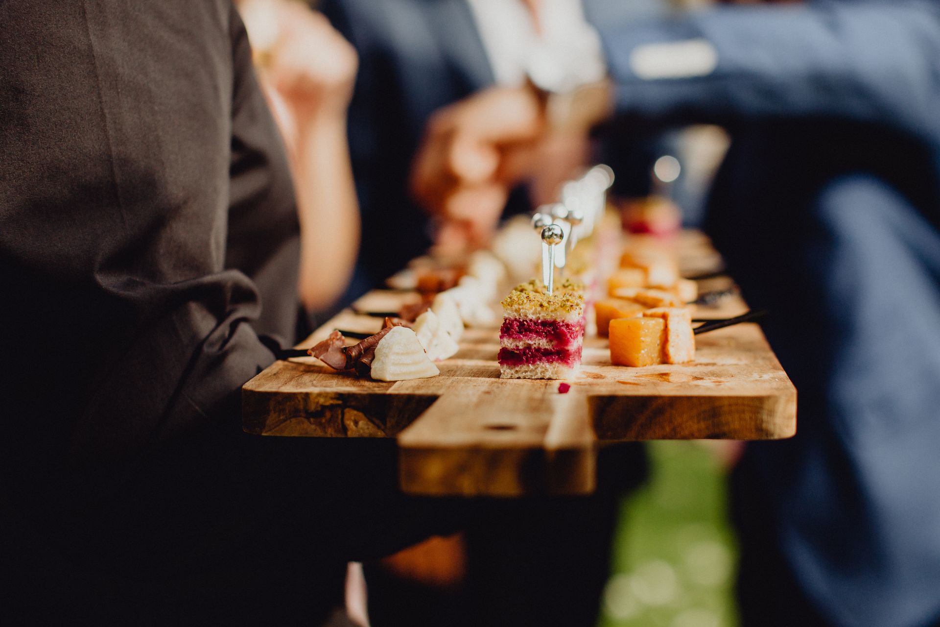 Plateau de service en bois garni d'amuse-gueules et de boissons variés lors d'une réception.