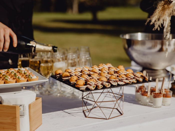 Buffet avec hors-d'œuvre, boissons servies et grand saladier lors d'un événement en plein air.
