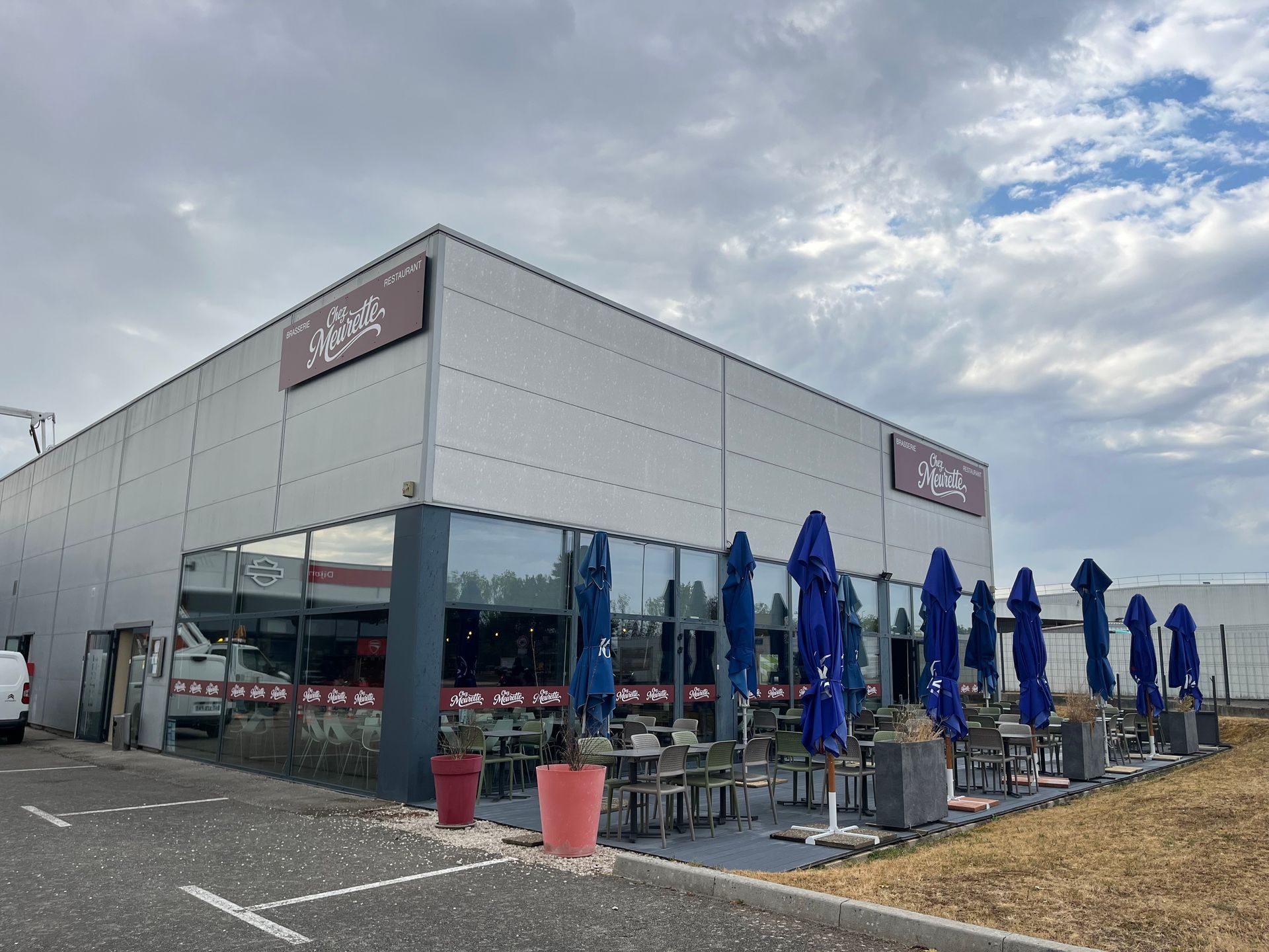Terrasse extérieure de Chez Meurette avec parasols bleus et tables.
