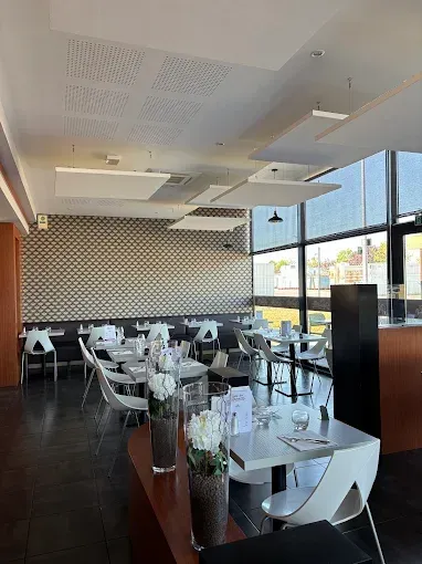 Salle de restaurant de Chez Meurette avec tables blanches, chaises noires et grandes fenêtres donnant sur l'extérieur.