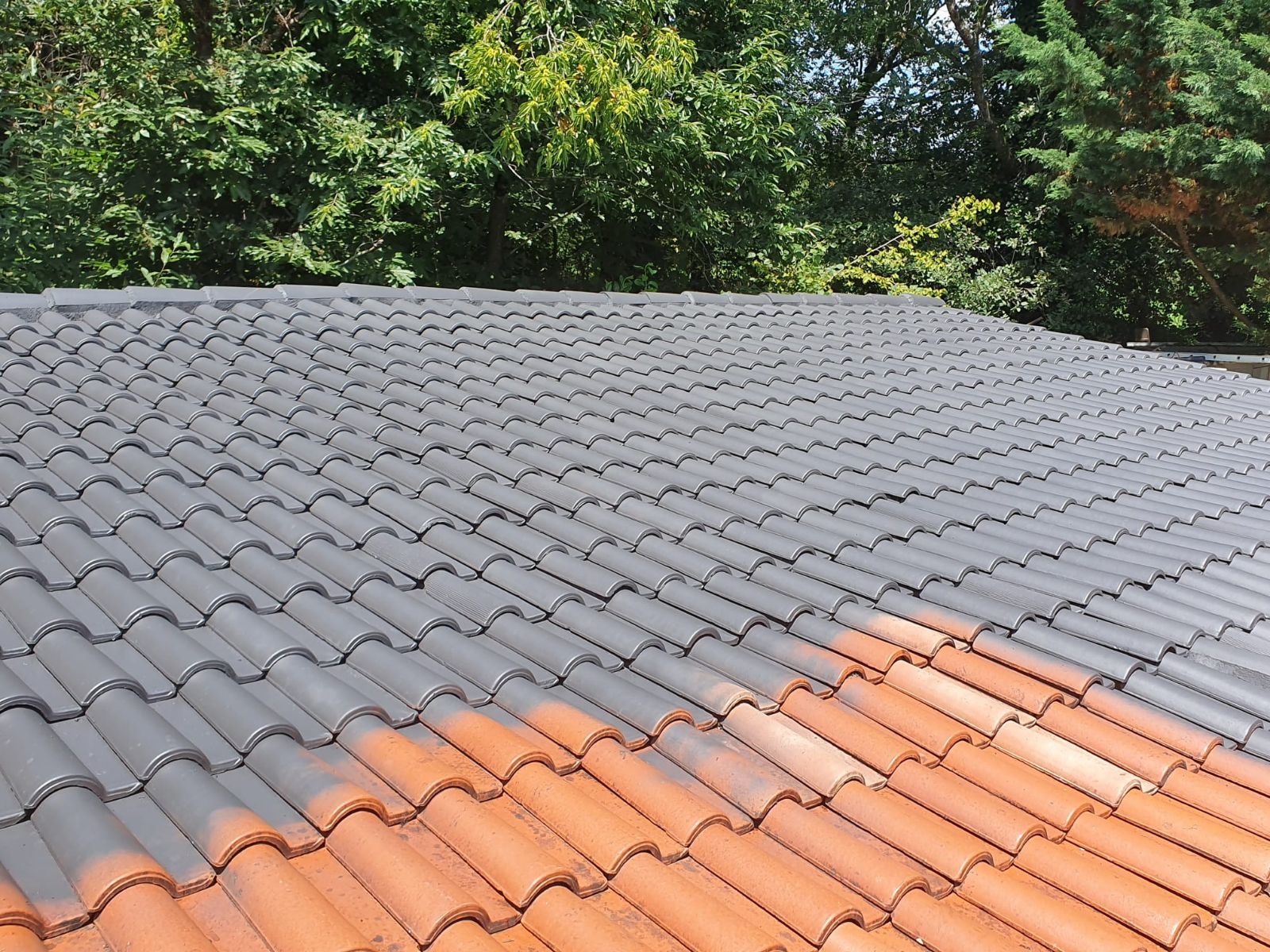 Une toiture en tuiles peintes en gris, contrastant avec les tuiles orange d'origine