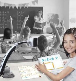 Lächelndes Mädchen mit Tablet im Klassenzimmer. Schüler heben Hände. Lehrer im Hintergrund. Schwarz-Weiß-Einstellung.