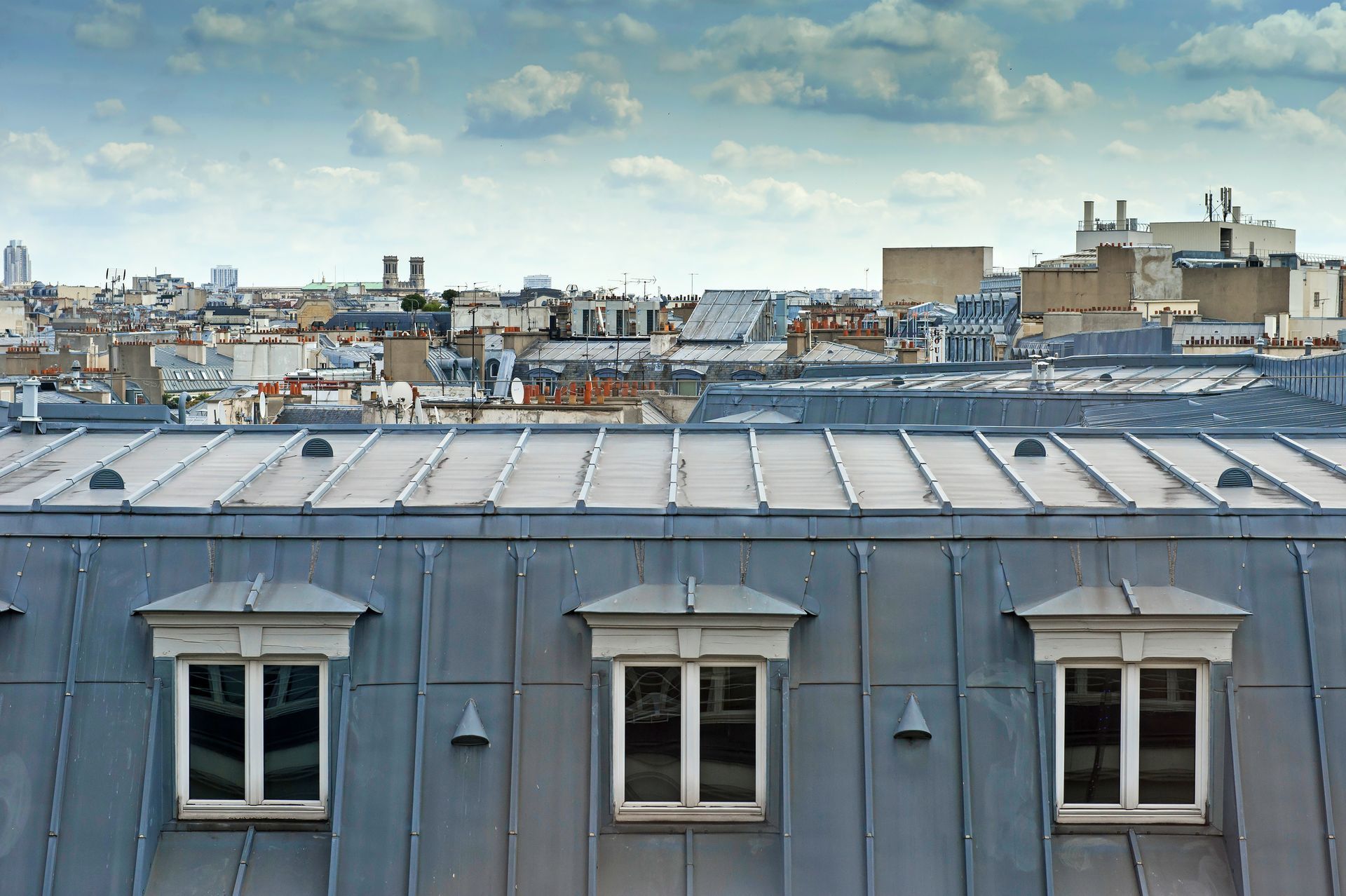 Toit-terrasse avec lucarnes grises donnant sur la ligne d'horizon de la ville sous un ciel nuageux
