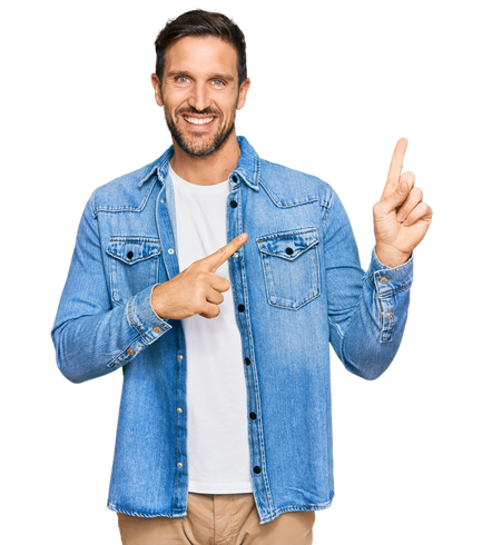 Homme souriant en veste en jean bleue pointant vers le haut et sur le côté sur fond blanc