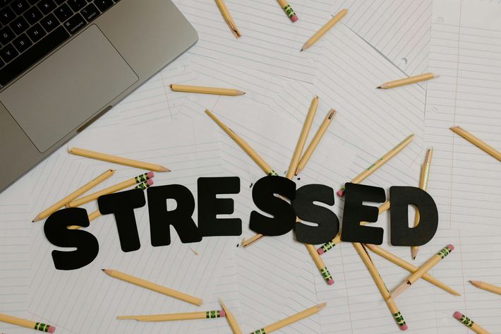 Schreibtisch mit verstreuten Stiften und dem Wort „STRESSED“ in fetten schwarzen Buchstaben.
