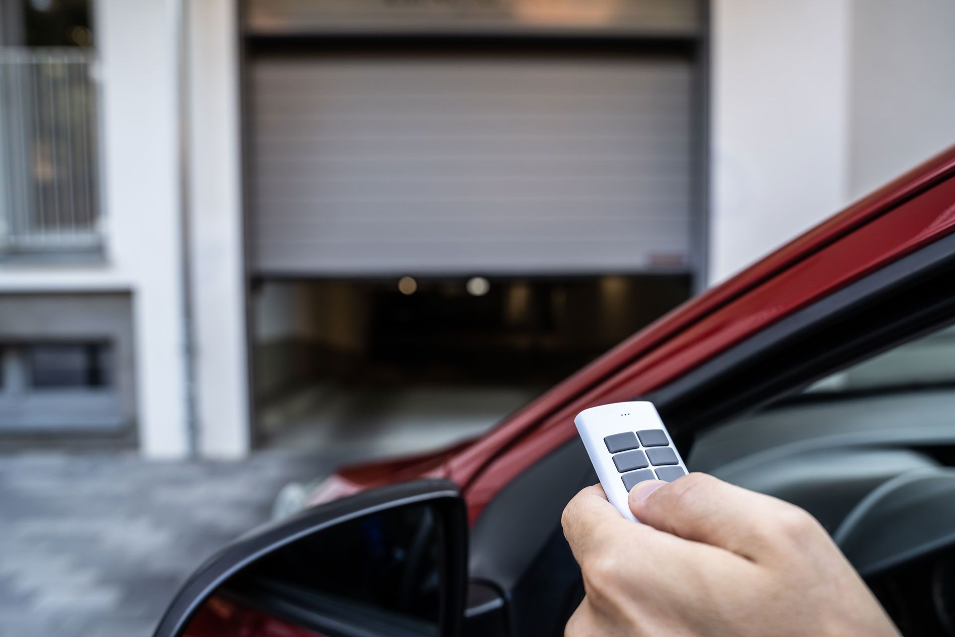 Une personne ouvrant son garage depuis sa voiture à l'aide d'une télécommande