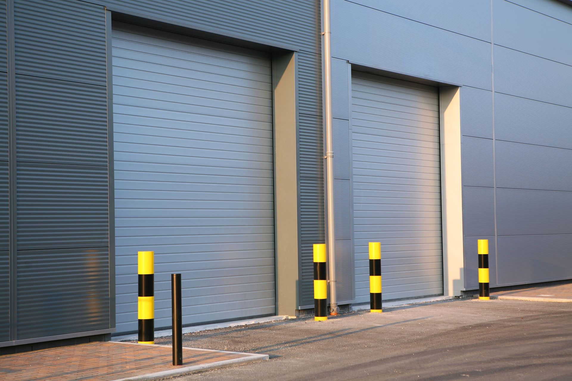 Deux portes de garage sectionnelles avec des bornes jaunes et noires à côté