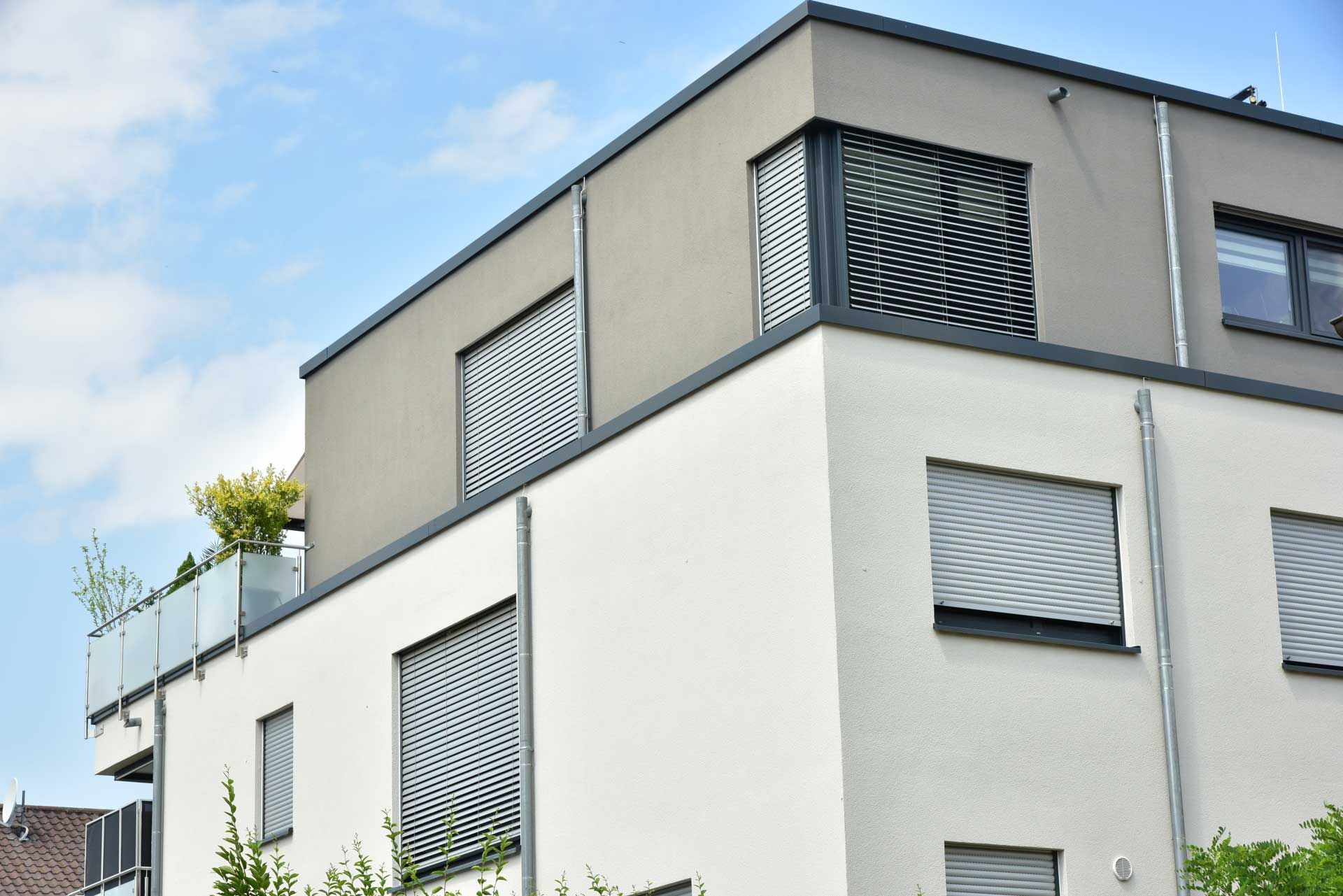 Façade de bâtiment à étages avec fenêtres occultées par des volets roulants et des stores