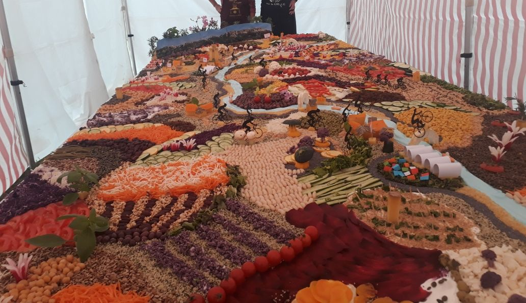 Sur une table des légumes de toutes les couleurs posés en lignes et formes géométriques représentant un paysage