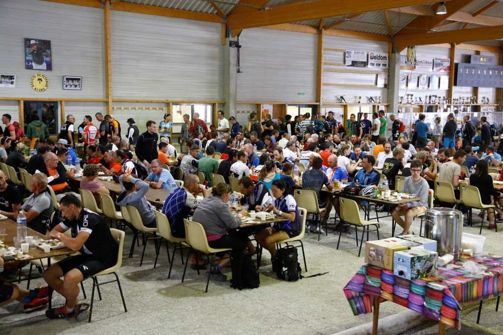 Repas Chemins du Soleil Dans un grand hangar, un grand nombre de personnes atablées