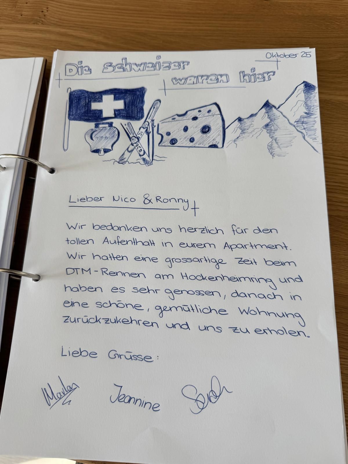 Handgeschriebener Brief mit blauen Tuschezeichnungen einer Flagge, eines Käses und von Bergen auf weißem Papier