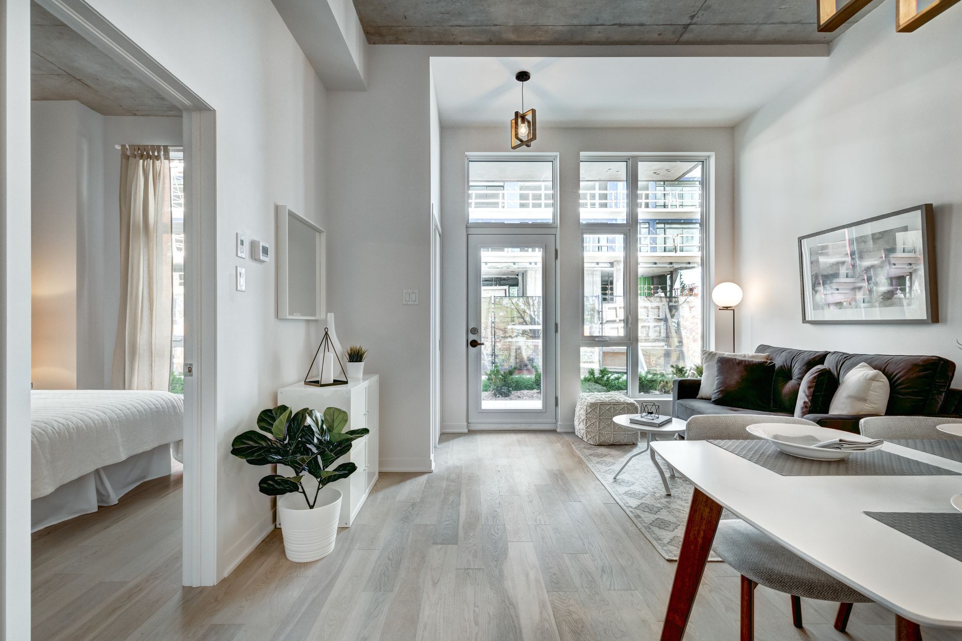 Helles, modernes Studio-Apartment mit Schlafnische, Wohnbereich und Glastüren zum Balkon.