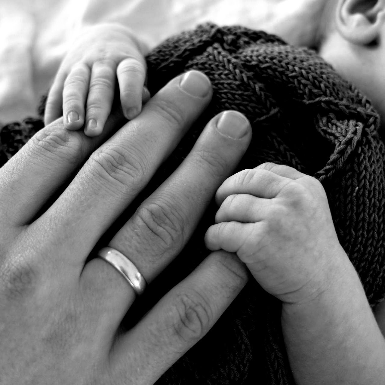 Ein Schwarzweißfoto einer Person, die die Hand eines Babys hält