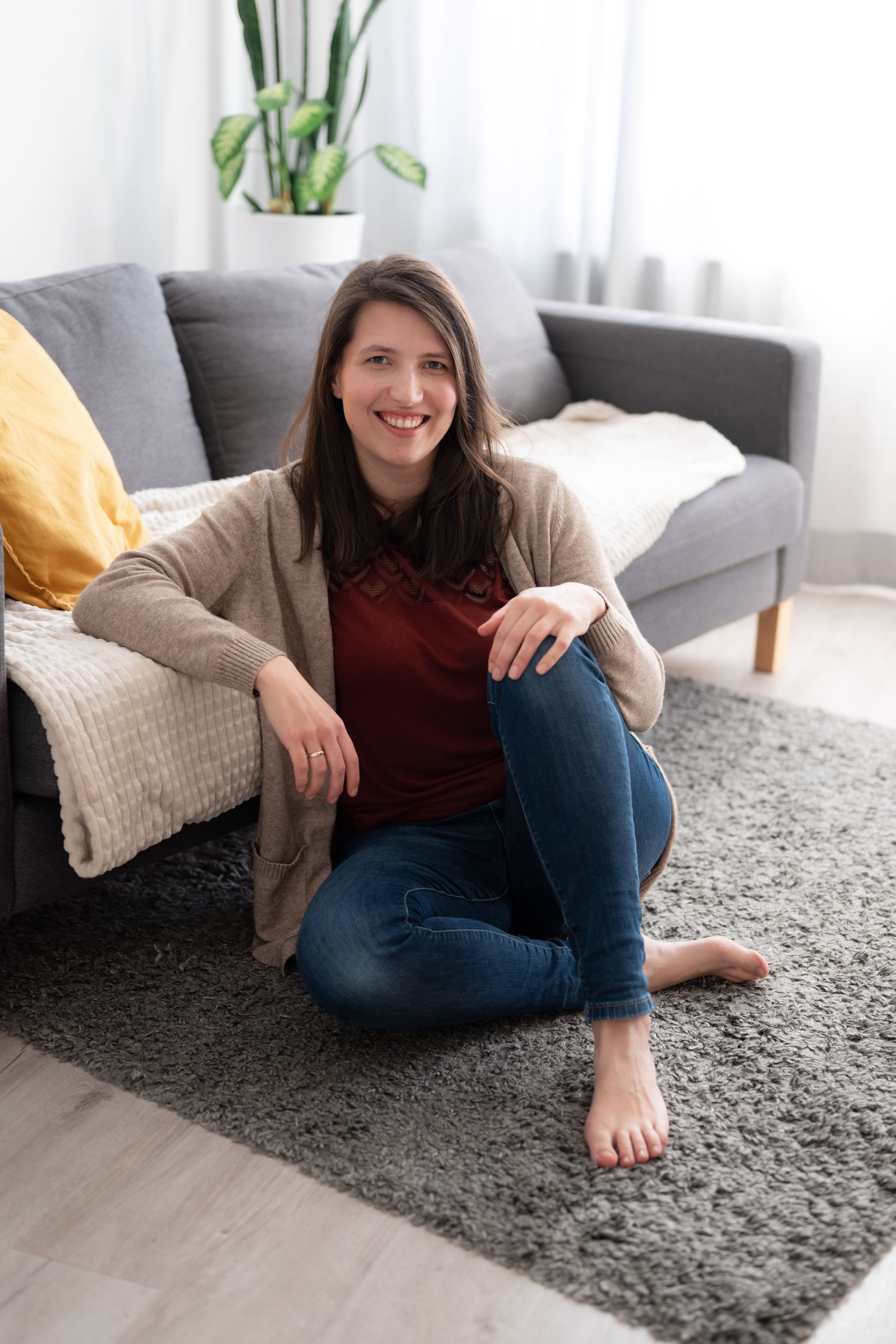 Marie sitzt auf dem Boden vor einem Sofa.