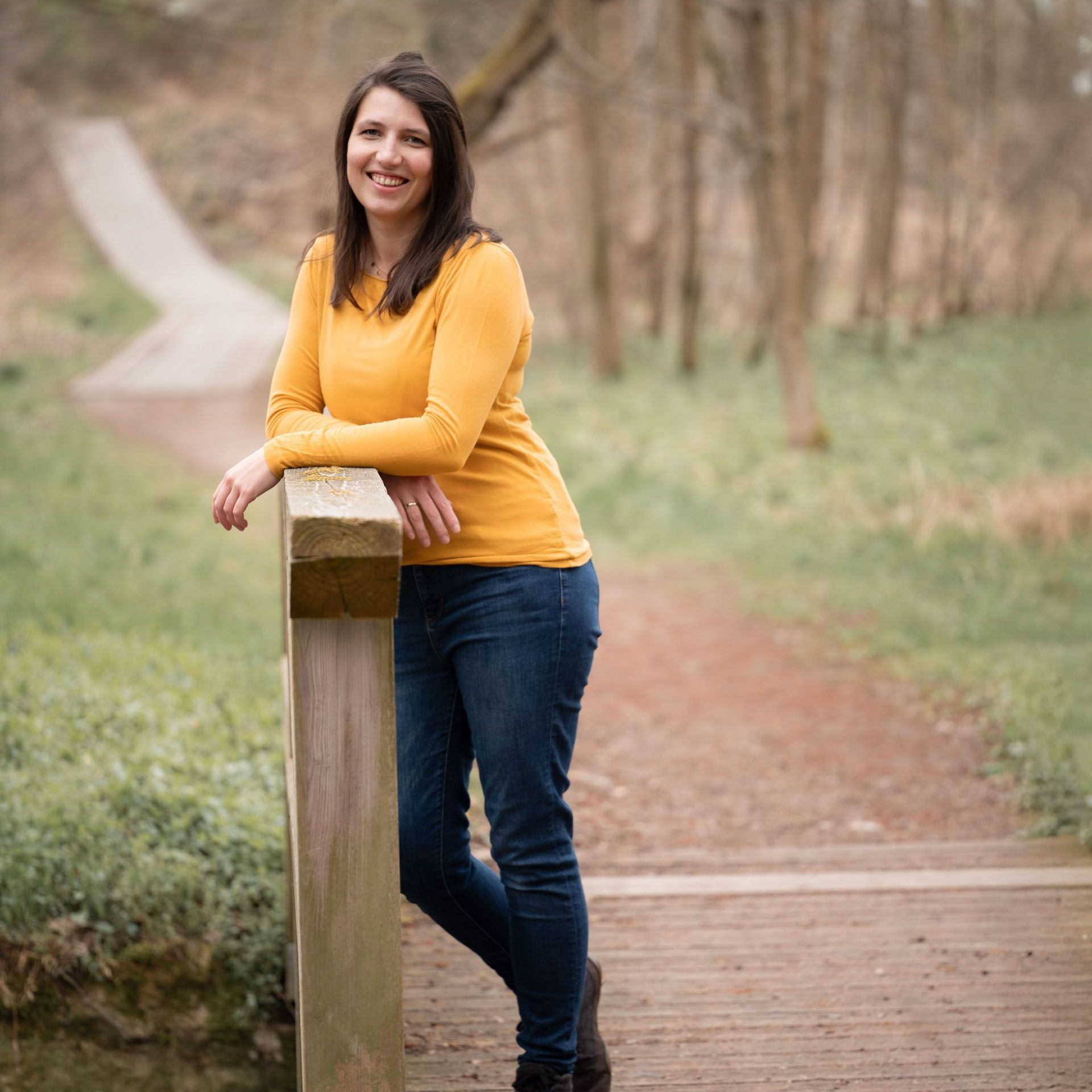 Marie lehnt an einem Baum im Wald