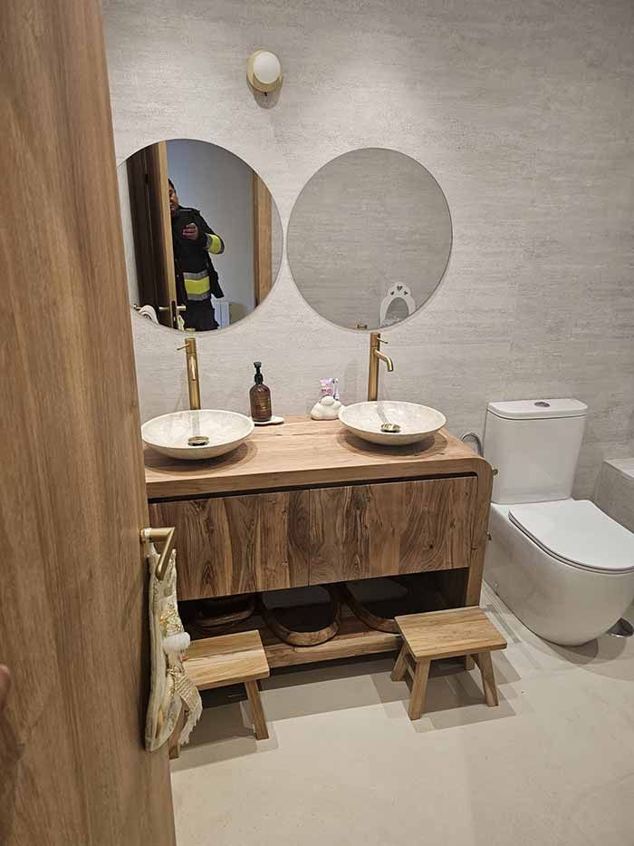 Un baño con dos lavabos, un inodoro y dos espejos.