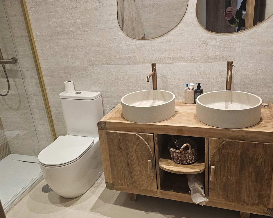 Un baño con dos lavabos, un inodoro y dos espejos.
