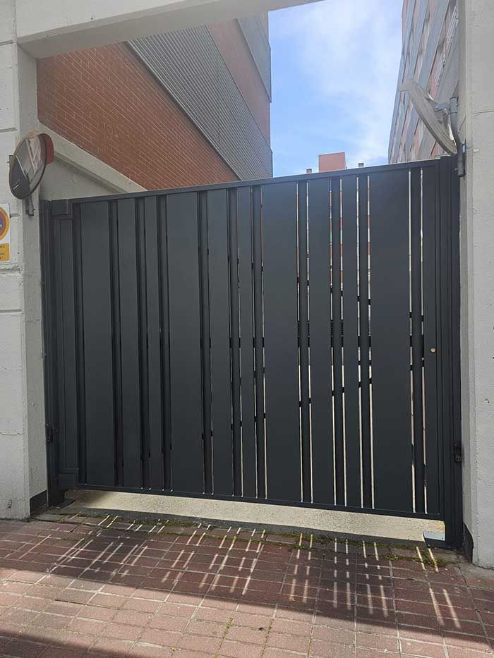 Una puerta de metal negro se encuentra frente a un edificio.