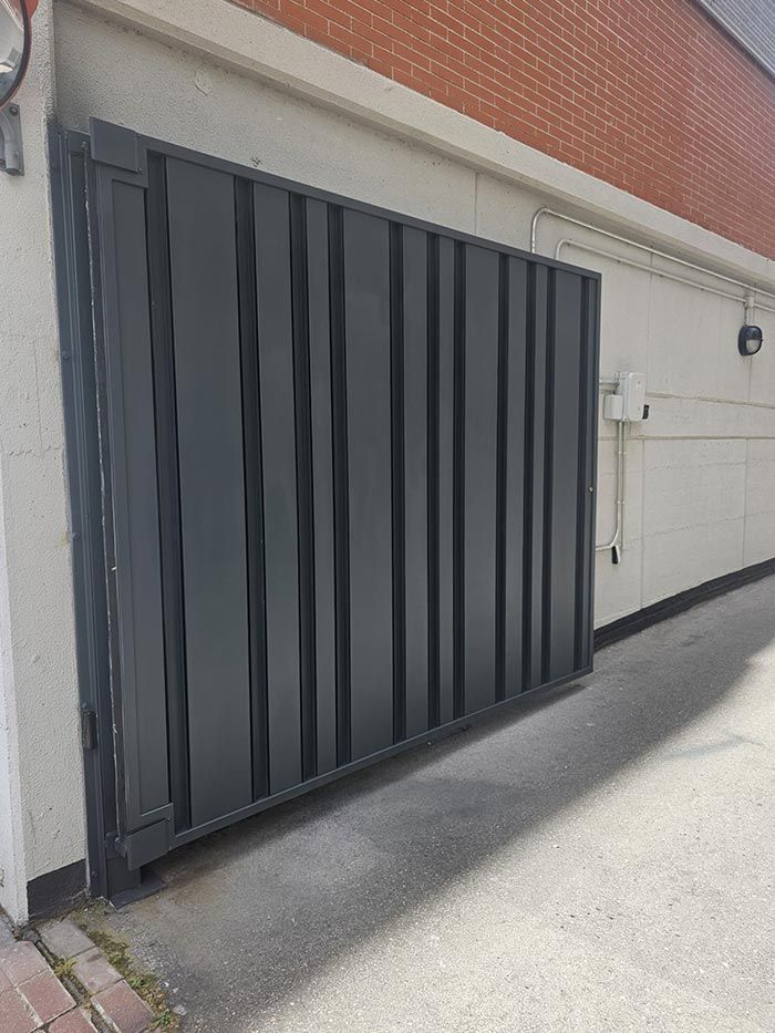 Una puerta corrediza negra está sentada al costado de un edificio.
