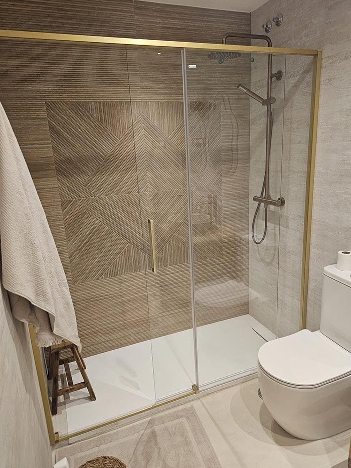 Un baño con inodoro y cabina de ducha con puertas corredizas de cristal.