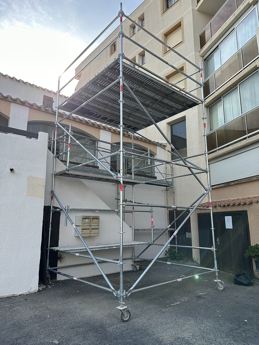 Un échafaudage avec des roulettes devant une maison