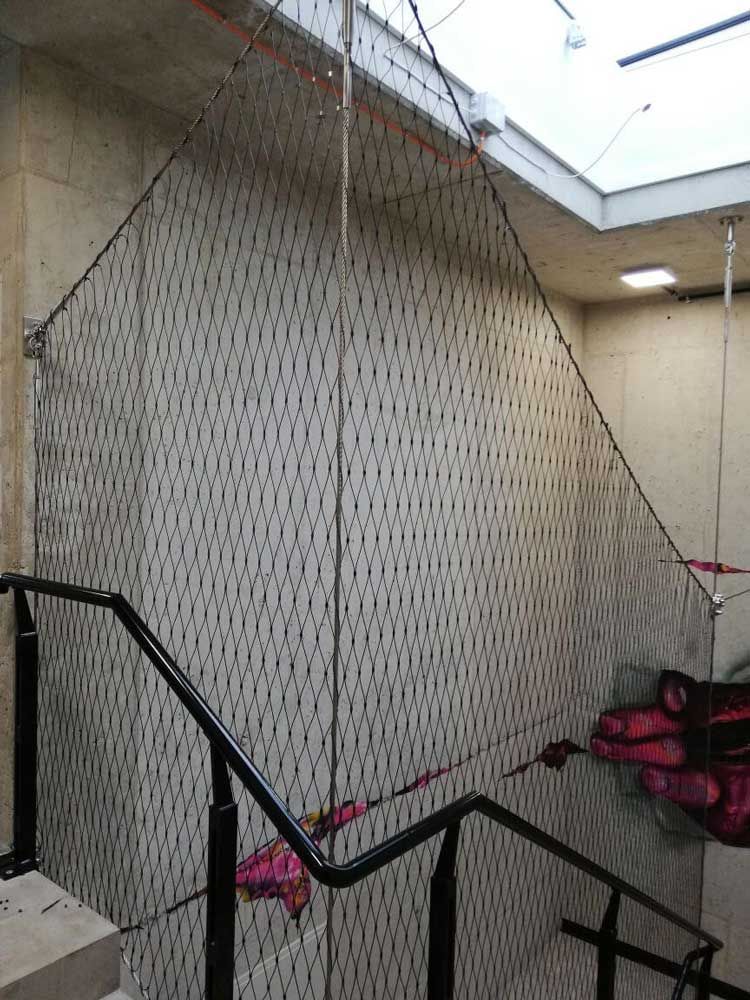 Netz aus Metall an einem Treppengeländer