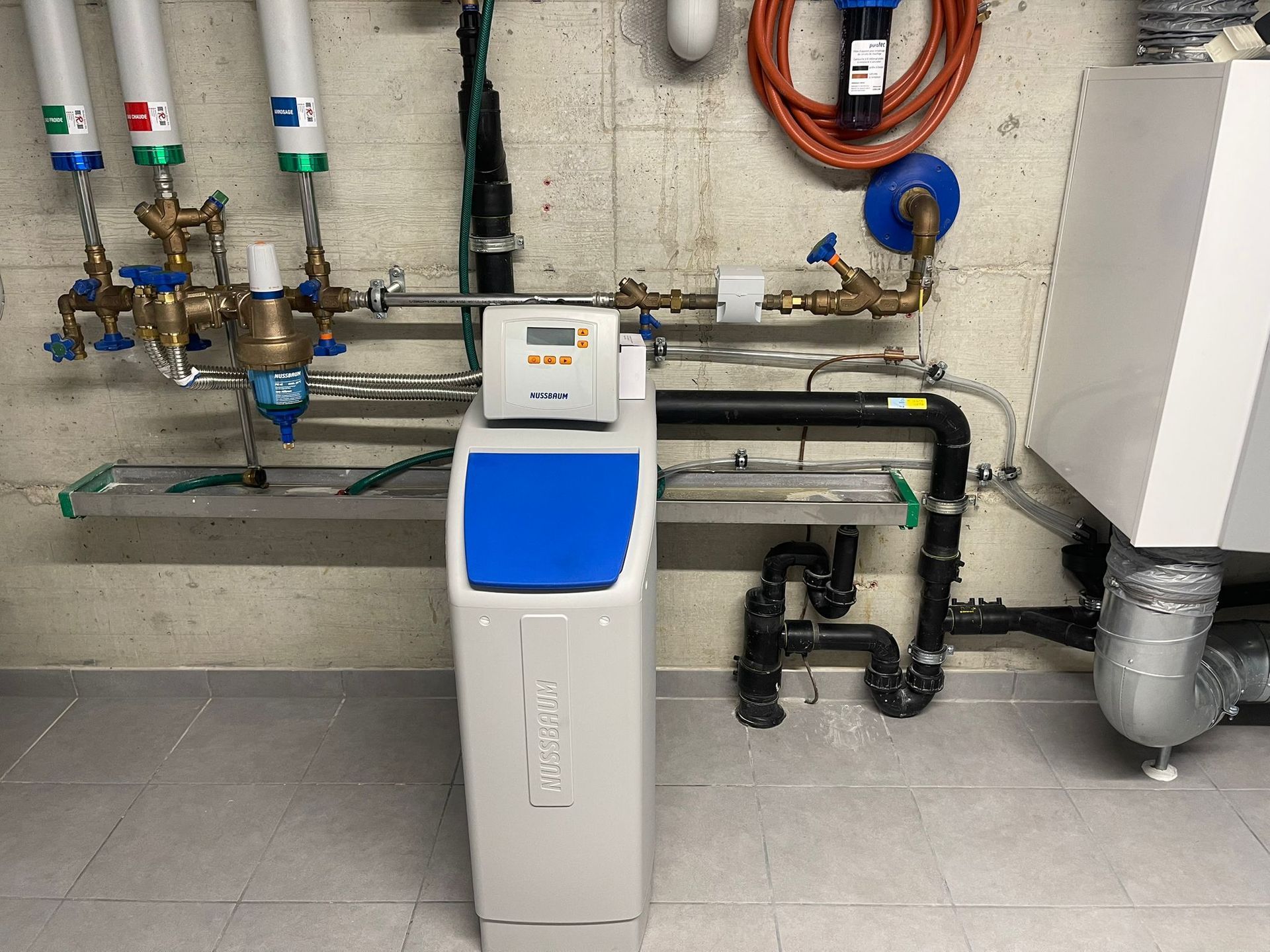 Système de filtration et d'adoucissement de l'eau installé sur un mur en béton.
