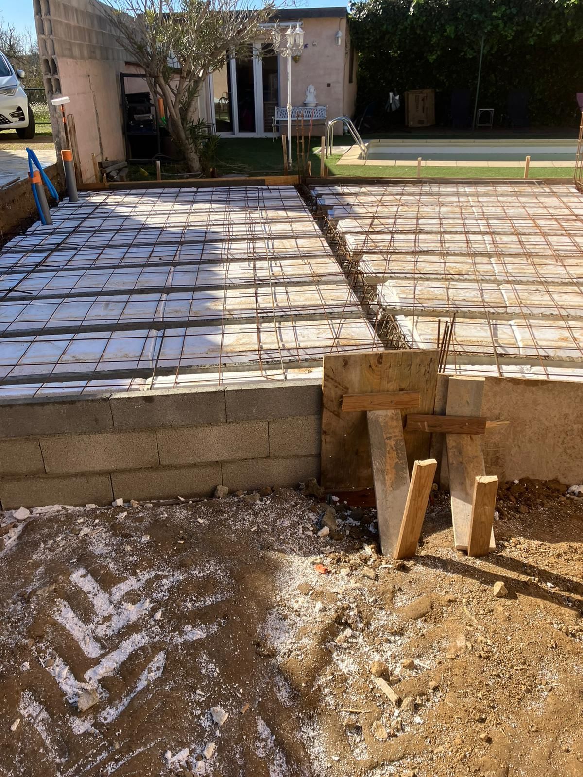 Chantier : fondation en béton avec fer à béton, isolation et mur de soutènement.