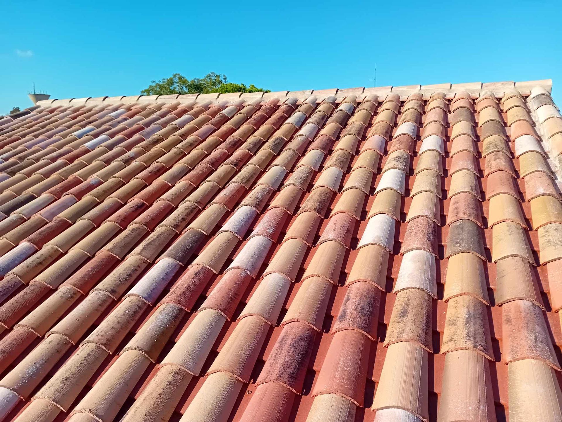 Toit en tuiles d'argile incliné contre un ciel bleu clair.