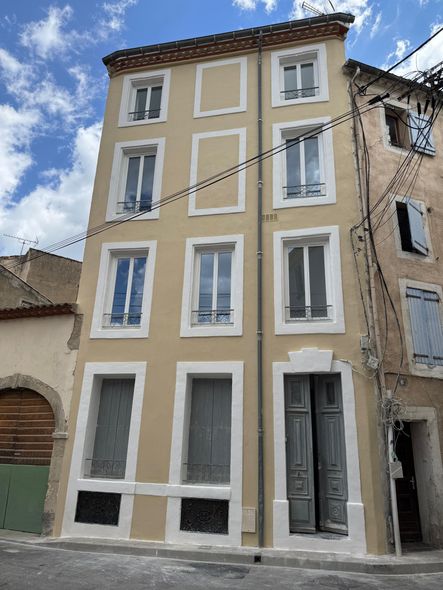 Un grand bâtiment de couleur crème avec plusieurs fenêtres dans une ville européenne.