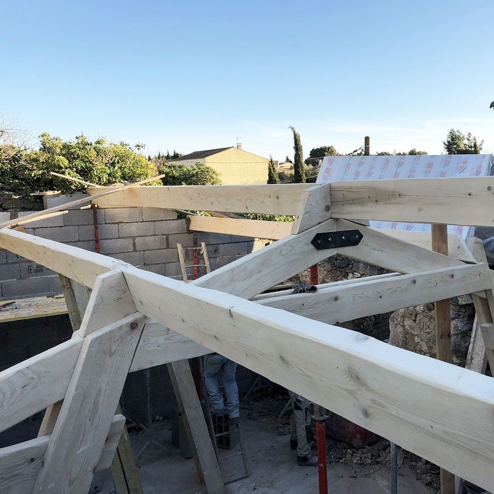 Fermes de toit en bois en cours d'assemblage sur un bâtiment en construction à l'extérieur, avec un ciel bleu