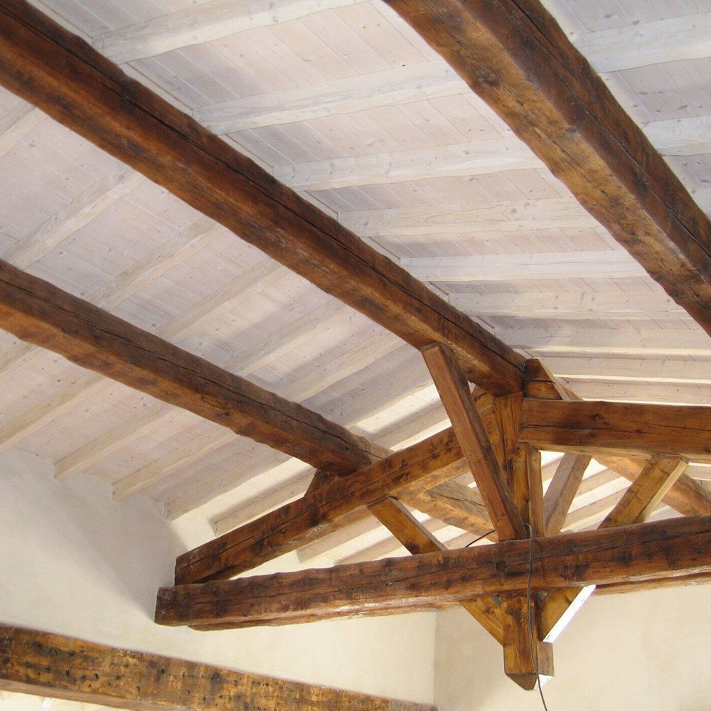 Poutres et chevrons en bois au plafond d'une pièce, avec un plafond peint en blanc entre eux.