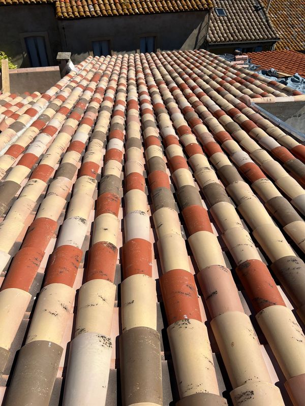 Rangées de tuiles en terre cuite et de couleur crème sur un toit, vues d'une perspective élevée.